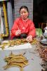 Китаянка в красном торгует свежими миногами на улице в Шанхае