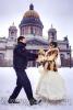 Зимняя свадебная прогулка в Санкт-Петербурге, молодожены кружатся под снегопадом, взявшись за руки, на фоне Исаакиевского собора