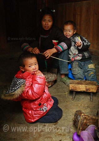 A Chinese peasant family sits in the interior of their house, near Congjiang, Rongjiang, Kaili, China